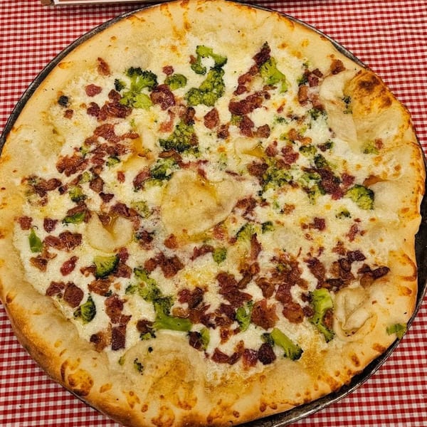 Tharptown General Store & Pizzeria's white pizza with broccoli, bacon, and garlic on a red checkered tablecloth.
